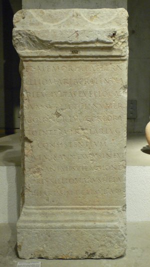 D(iis) M(anibus) / et memoriae aetern(ae) / Illiomari Apri, lintia/ri(i), ex civitate Veliocas/sium, sublecto in numer(um) / colonor(um) Lug(udunensium), corpora/to inter utriclar(ios) Lug(duni) / consistentium, / qui vix(it) ann(os) LXXXV sine ul/lius animi sui laesione, / Aprius illiomarus, fil(ius), pa/tri karissim(o) p(onendum) c(uravit) et sub a(scia) d(edicavit)
[Aux dieux Mânes et à la mémoire éternelle d'Illiomarius Aper, marchand de toiles (de chanvre et de lin), de la cité des Véliocasses, admis au nombre des colons de Lyon, membre de la corporation des utriculaires demeurant à Lyon mort à l'âge de 85 ans, sans avoir jamais fait à personne aucune peine ; Aprius Illiomarus, son fils, a élevé ce tombeau à son père très cher et l'a dédié sous l'ascia.] 